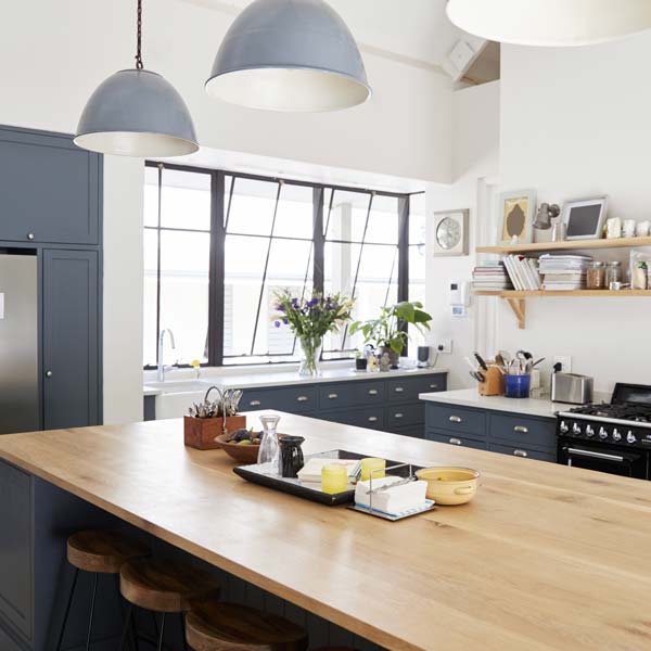 Modern country styled kitchen with a beach countertop and dark blue cupboards.