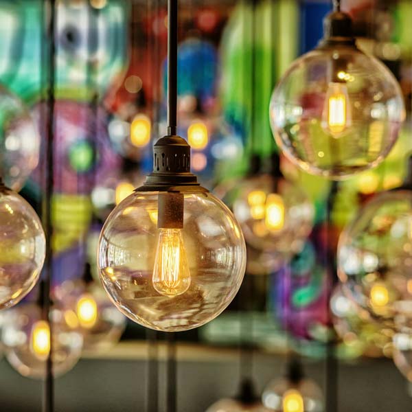 Close up of a modern LED vintage looking lightbulb with many other lights in the background out of focus. Bokeh.