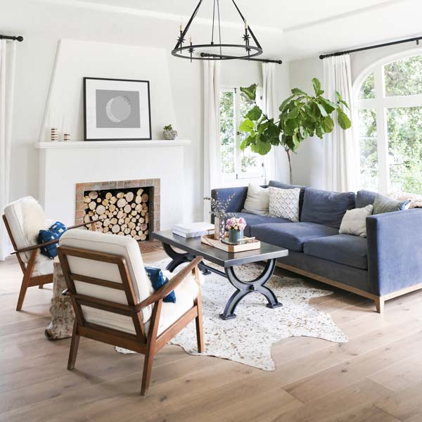 Airy light living room showing a pastel blue sofa in room with white chairs, rug and walls.